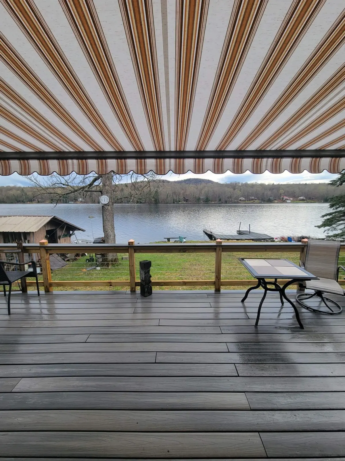 Sunair striped retractable awning shading a lakeside deck.